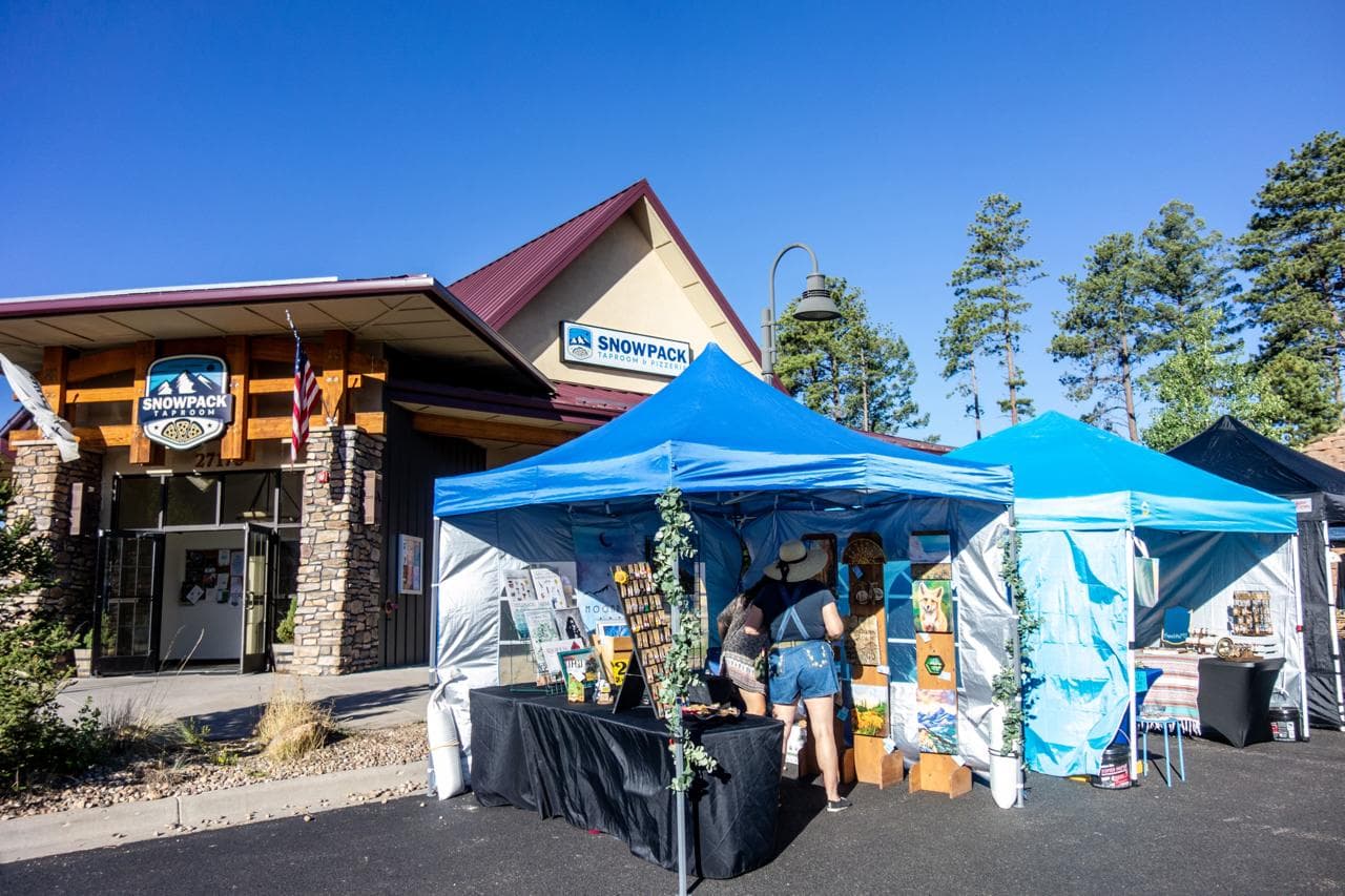 Vendor tents set up at the Snowpack Taproom entrance beneath the pines