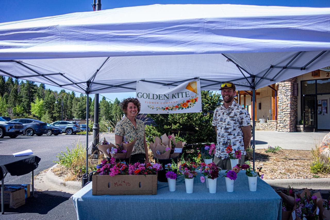 Golden Kite Flower Company's booth, buckets of fresh cut flowers on a blue tablecloth