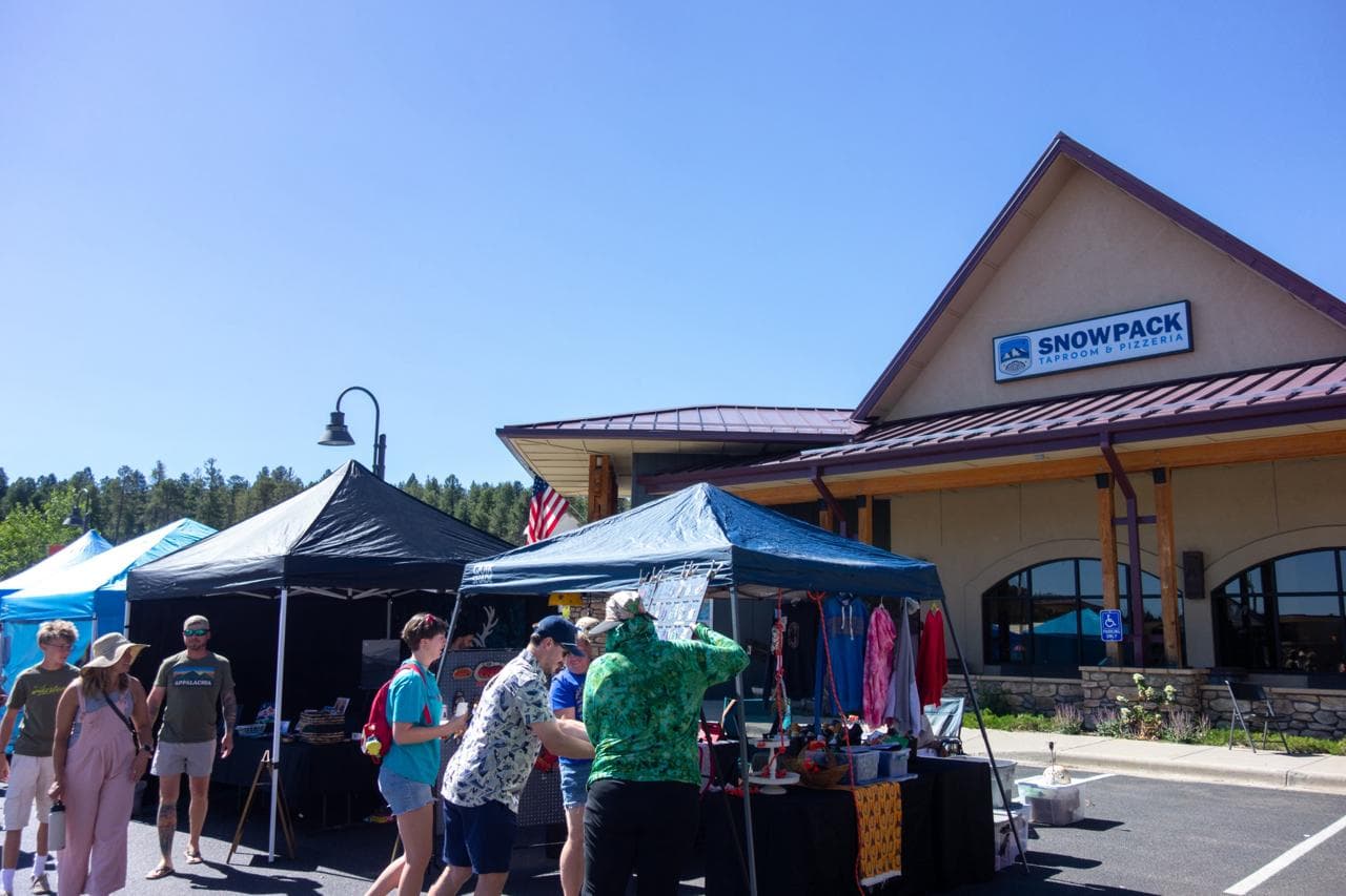 Tents along the front of the building, shoppers moving between booths