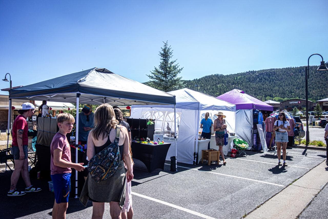 Shoppers browsing vendor tents outside Snowpack Taproom on a clear Sunday morning